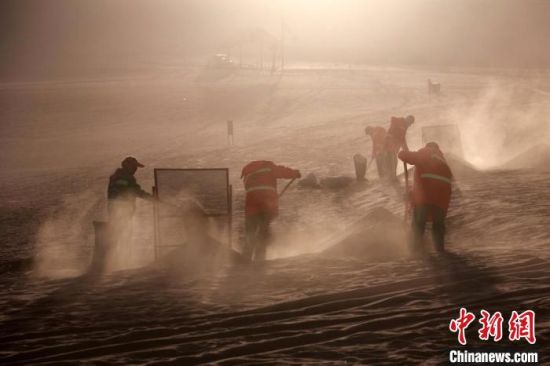 圖為敦煌市鳴沙山月牙泉景區(qū)“駱駝保姆”清理駱駝糞便?！垥粤?攝