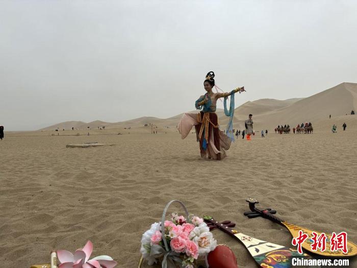 圖為2023年4月底，敦煌大漠“逐舞者”奧楠在鳴沙山月牙泉景區(qū)視頻直播敦煌舞?！●T志軍 攝