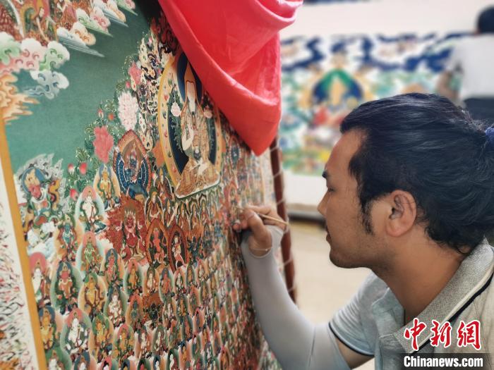 圖為更登才讓的徒弟繪畫唐卡?！?zhí)砀?攝