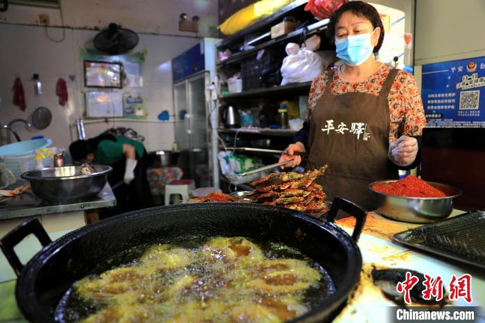 圖為平安驛·河湟民俗文化體驗(yàn)地內(nèi)的商戶炸干板魚?！⊙Φ?攝